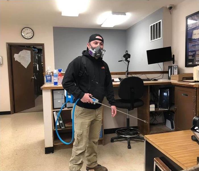 SERVPRO technician applying disinfectant to office setting