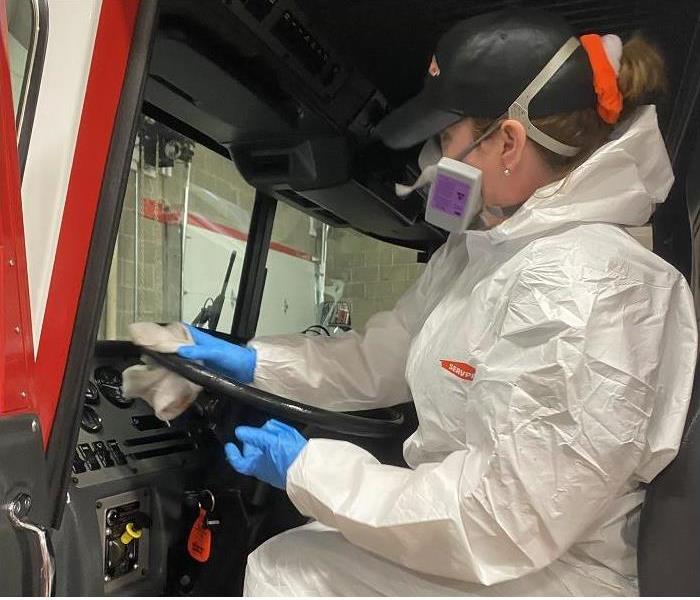 SERVPRO techincian dressed in PPE cleans fire truck