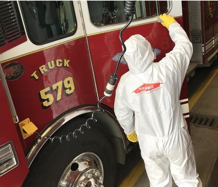 SERVPRO tech, dressed in PPE, cleaning fire truck