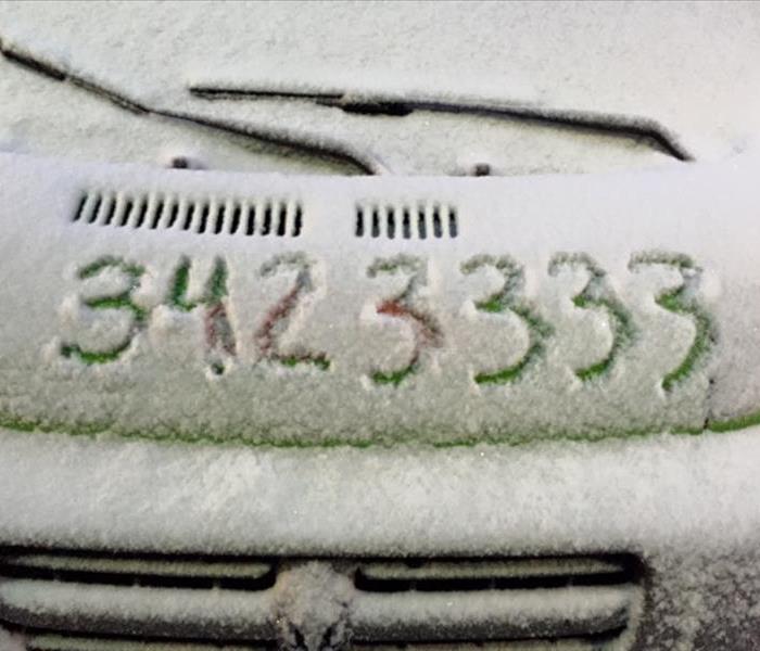 Snow covering a vehicle with the numbers 3423333 written in the snow